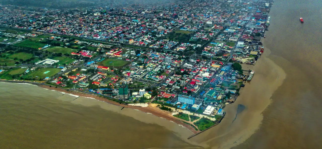Aerial view of Georgetown on the Atlantic coast, with dense streets running to wharves along the brown water of the Demerara River estuary